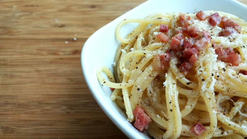 Spaghetti alla Carbonara mit gewürfeltem Speck, geriebenem Käse und schwarzem Pfeffer